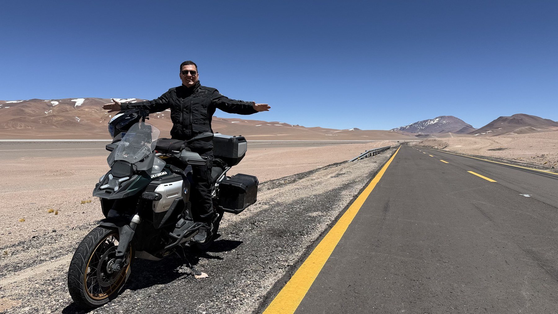 Rafael Barreto com sua moto em uma estrada entre montanhas